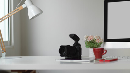 Computer desk with camera, smartphone, flower vase and copy space, clipping path