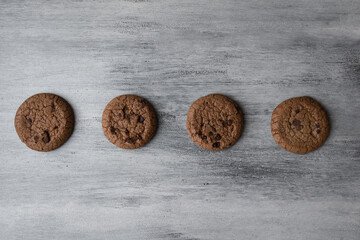Oatmeal cookies and pieces of chocolate on white wooden background