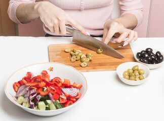 Slicing green olives on a cutting Board to add to a salad