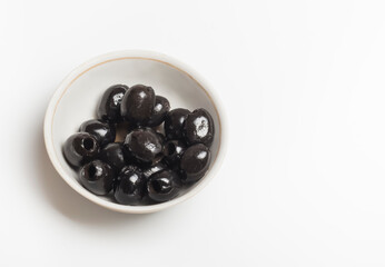 black olives in a white bowl on a white background with a copy of the space