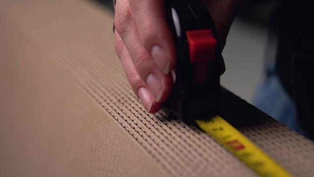A person measures the length of a brown&nbsp;cardboard