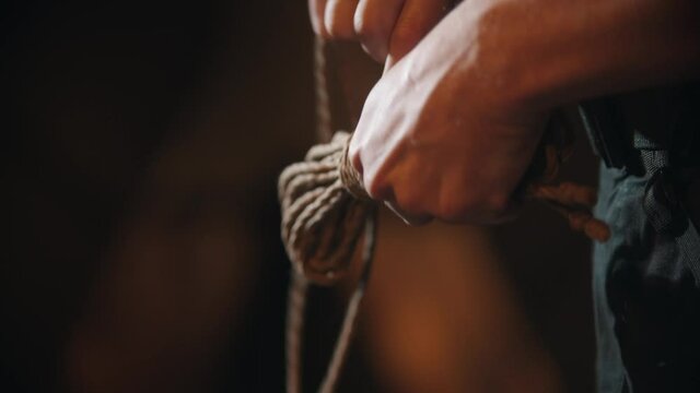 BDSM concept - imperious man holds ropes and twists them into a skein