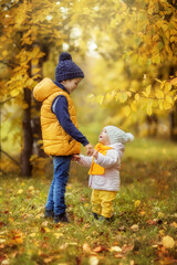 Fototapeta premium boy and girl brother and sister walking in the Park in autumn, laughing, playing, October, yellow leaves, Golden autumn, happy childhood