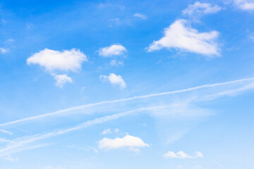 old contrail between cumuli clouds in blue sky on autumn day