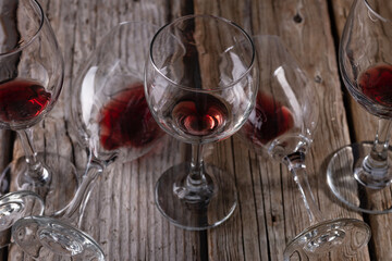 Close-up view of glass with the remains of red wine on glasses lie on a rustic wooden background....