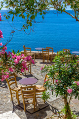Traditional cafe exterior in the fortified medieval  castle of Monemvasia. Iron tables and wooden chairs with the view of the  aegean sea in the background.