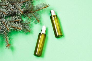 Skin care cosmetics bottles on a fir branches background. Blank containers on a green background. Christmas present for women. Winter season cosmetics. copy space, flat lay.
