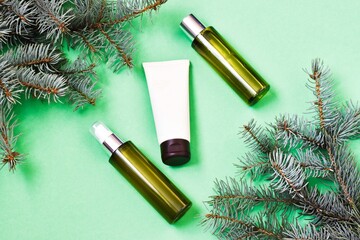 Skin care cosmetics bottles on a fir branches background. Blank containers on a green background. Christmas present for women. Winter season cosmetics. copy space, flat lay.