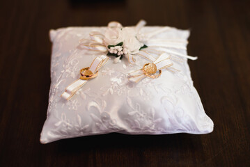 two gold wedding traditional rings on a white cushion