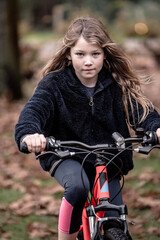 Fototapeta premium cute little girl on her bicycle in the garden or in nature