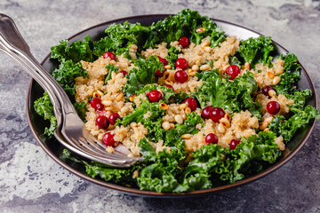 Healthy raw kale and quinoa salad with cranberry and pine nut.