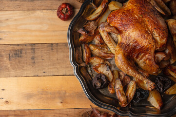 Top view of dish with baked turkey and potato near autumn pumpkin on wooden background. Concept of festive dinner. Traditional recipe.
