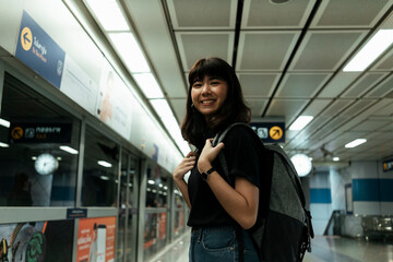 Happy asian woman waiting for a train in metro station.