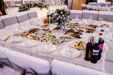Serves dinner on a festive table. Food, Salads, Meat, Fish Meals. Festive table at wedding banquet. Decor. Details.