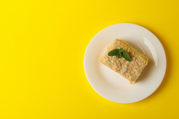 Plate with delicious Napoleon cake on yellow background
