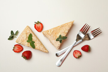 Pieces of Napoleon cake, strawberry and forks on white background