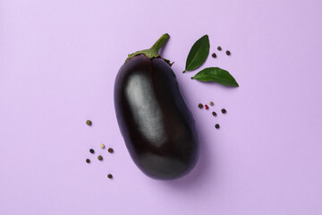 Fresh raw eggplant and peppercorns on violet background
