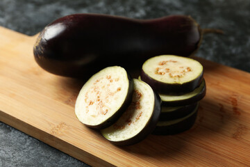 Board with eggplants on black smokey background
