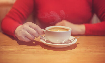 A girl drinks coffee at a table in a cafe
