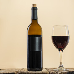 Elegant wine bottle and glass with red wine stands on the rustic wooden table on white background. Space for text. Advertisement concept.