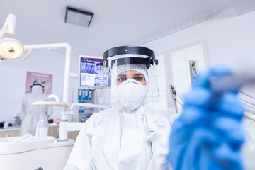 Dentist pov checking patient teeth hygine using drill to fix dental cavity. Stomatolog wearing safety gear against coronavirus during heatlhcare check of patient.