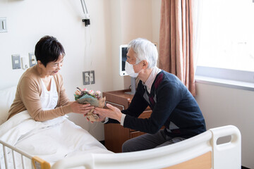 Obraz premium 入院中の妻に花をプレゼントする夫