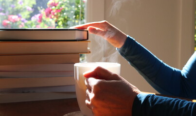Mature woman with a steaming hot herbal tea and a selection of books