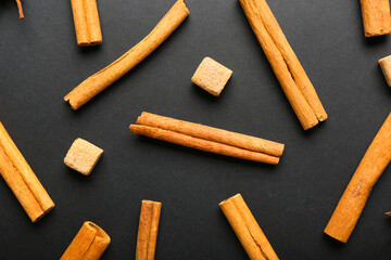Cinnamon sticks and sugar on dark background