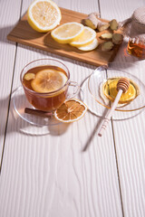 Vitamin tea in a glass Cup with lemon, honey and ginger on a wooden cutting Board, white background.Close up. Vertical orientation. Copy space