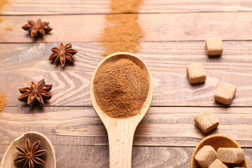 Spoon with cinnamon powder, anise and sugar on wooden background
