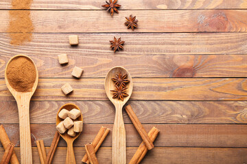 Spoons with cinnamon, anise and sugar on wooden background