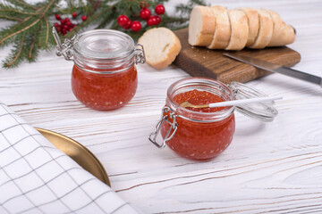 Red caviar in jar on aged white wooden background. Main dish New Year