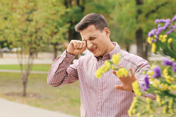 Young man suffering from pollen allergy outdoors