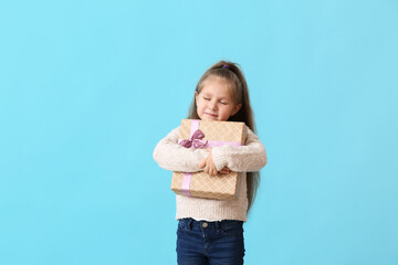 Cute little girl with gift on color background