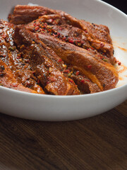 Raw pork belly slices in Korean style marinade on a white plate. Meat industry product