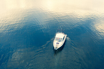 Fototapeta premium Aerial view fisherman on boat at the ocean. Top view beautiful seascape with the fishing boat. Aerial view fishing motor boat with angler. Ocean sea water wave reflections. Motor boat in the ocean.