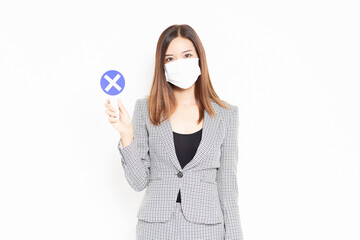 NGのプレートを持つマスクをしたビジネスウーマン