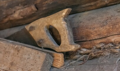Old saw with a wooden handle closeup against a log wall