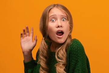 Image of shocked blonde teen expressing surprise on camera. Studio shot, yellow background. Human...