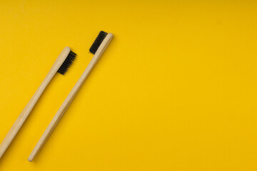 Two biodegradable wooden oral hygiene accessories on yellow background  . Zero waste, plastic free, sustainable lifestyle concept. Copy space