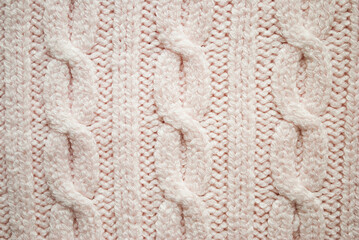 Texture of pink knitted sweaters ornament. Chain Cable stitch knit fabric background closeup, soft focus