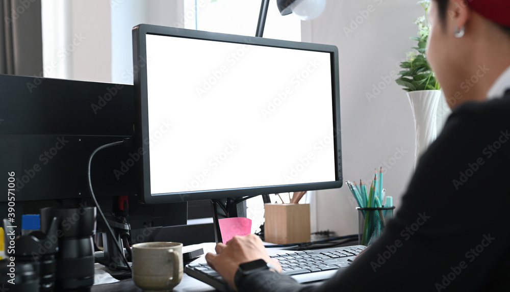 Poster cropped shot of a young designer sitting at graphic studio in front of computer while working online
