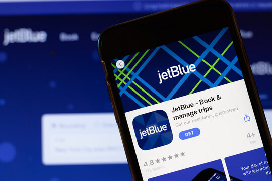 Los Angeles, California, USA - 24 March 2020: JetBlue app logo on phone screen close up with website on background with icon, Illustrative Editorial