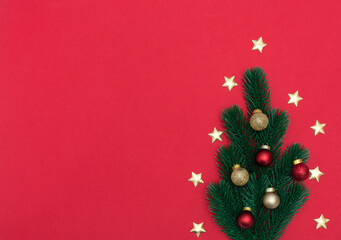 Christmas tree made of spruce with Xmas decorations on red background. New Year, winter greeting card, poster. Flat lay style with copy space.