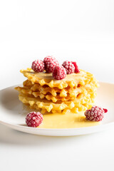 Weekend breakfast: waffles with condensed milk and raspberries. White background. Viennese waffles with condensed milk and raspberries on a white plate