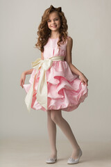 Pin-up girl teenager in a beautiful pink dress posing in the studio on a white background