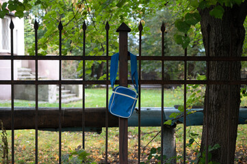 Fototapeta na wymiar Blue spitting bag with strip and place under your logo hangs on a metal fence with pins against the background of lawns and trees