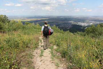 Man with a backpack descending the trail  from the mountain Tserkovka,  Altai, Russia