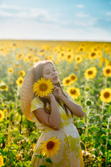 Beautiful caucasian pregnant woman walking in the summer at sunset in a field of blooming sunflower