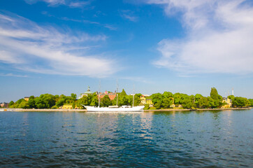 Fototapeta premium Watercolor drawing of White ship yacht boat hostel af Chapman with mast moored near Skeppsholmen island with green trees and old buildings and blue sky white clouds background, Stockholm, Sweden
